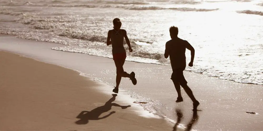 man and woman running on beach