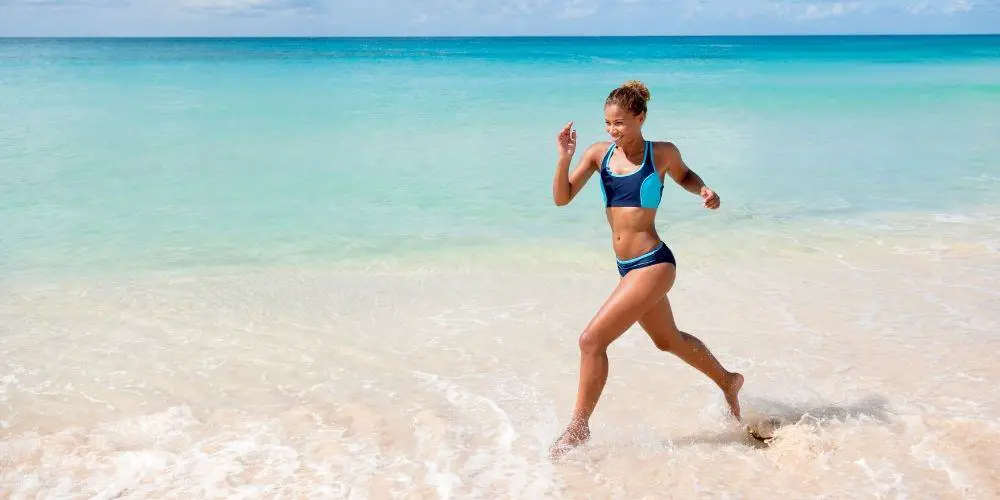 woman running barefoot on the beach